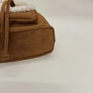 Macro detail of brown suede bucket bag with soft white shearling trim and knotted handle