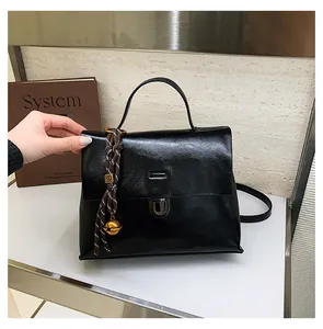 Detail der schwarzen Handtasche aus Leder mit geflochtenem Seil und goldenem Glocken-Anhänger