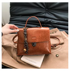 Detailaufnahme der dunkelbraunen Vintage-Aktentasche aus Leder mit goldenem Glockenanhänger