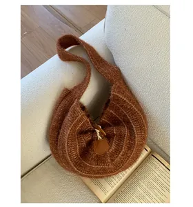 Detail of caramel knit crescent bag with wooden horn buckle and soft wool texture