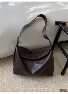 Dettaglio di una borsa tote vintage in pelle marrone scuro con tracolla e fibbia