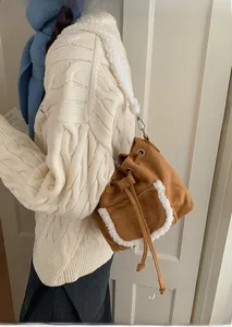 Detail of vintage brown suede bucket bag with white faux fur trim and shoulder strap