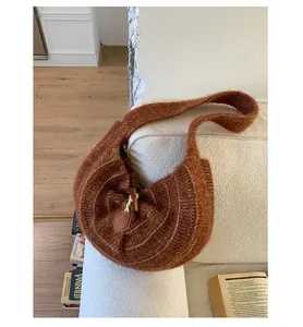 Detail of a brown knit shoulder bag with toggle closure on a cozy fabric sofa