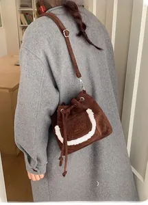 Detail view of a vintage dark brown suede drawstring bucket bag with fuzzy white trim detail