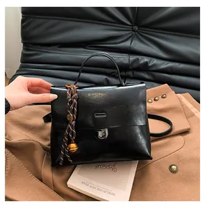 Detailansicht der schwarzen Lederhandtasche mit goldenem Drehverschluss und Anhänger