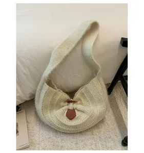 Detail of soft cream knit shoulder bag featuring vintage horn buckle and leather accents