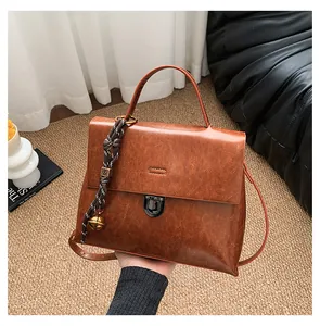 Details der Vintage-Handtasche in Karamellbraun mit Drehverschluss und Flechtanhänger
