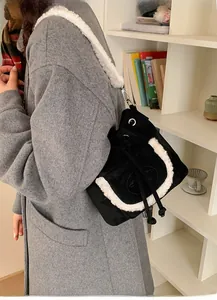 Detail of black faux suede bucket bag with white faux fur trim and wide shoulder strap