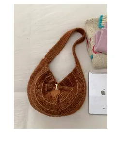 Detailed close-up of brown knit crescent shoulder bag with horn buckle and soft texture