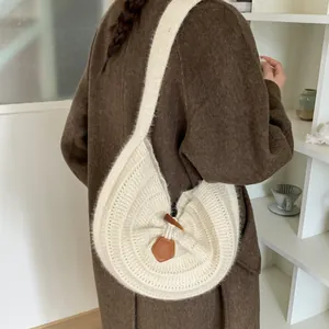 Chic cream knit round shoulder bag with leather toggle closure in a minimalist style