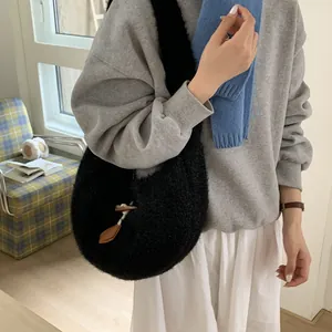 Minimalist black faux shearling shoulder bag with toggle closure in cozy indoor setting