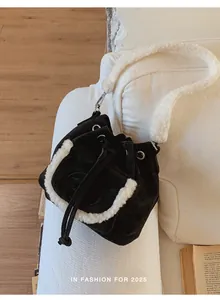 Close-up of black suede bucket bag featuring plush white faux fur trim and shoulder strap
