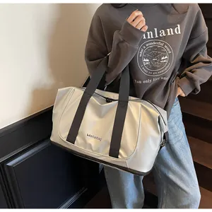 Primer plano del bolso tote plateado con correas negras y letras de marca grabadas