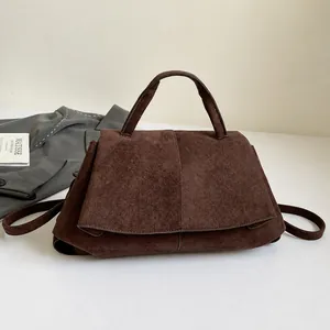 Dettaglio borsa in pelle scamosciata marrone scuro opaco con patta a trapezio