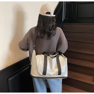 Detalle del bolso tote plateado de gran capacidad en nailon con asas y correa de marca