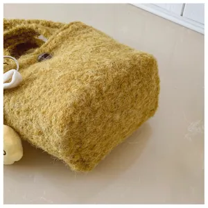 Detailaufnahme der ingwergelben Plüschtasche mit weicher Webpelz-Textur und Anhänger
