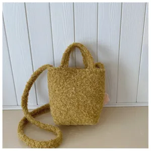 Detail der senfgelben Teddy-Plüsch-Eimertasche mit rosa Blumenanhänger-Dekor