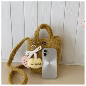 Detailansicht der ingwerfarbenen Plüschtasche mit Anhänger und Smartphone zum Vergleich