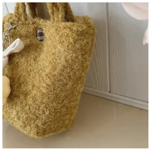 Detailaufnahme der ingwerfarbenen Plüschtasche mit Wolltextur und kariertem Knopf