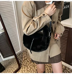Détail d'un sac bandoulière en fausse fourrure noire avec sangle en cuir et boucle métal