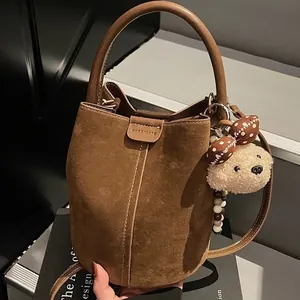 Brown suede bucket bag with CHERIMAYE lettering and bear charm for commute