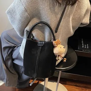 Vintage black suede bucket bag for women with cute teddy bear charm and contrast stitching