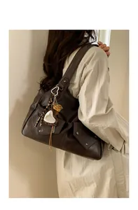 Detail view of retro brown shoulder bag with metallic rivets and leopard print heart charm