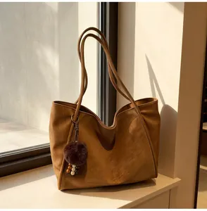 Détail d'un sac cabas en daim marron avec breloques sous une douce lumière naturelle