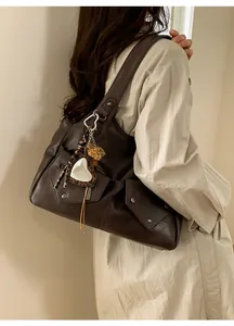 Detail view of dark brown vintage shoulder bag with metal rivets and leopard heart charm