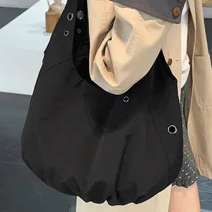 Minimalist black oversized hobo tote bag with silver grommets for stylish commuting