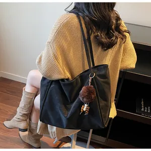 Détail d'un grand sac cabas noir en suède avec breloque en peluche pour le quotidien