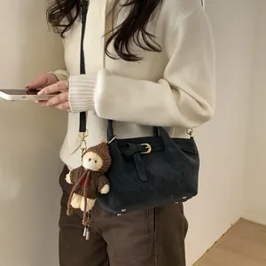 Black suede bucket bag with gold buckle detail and cute brown bear charm on the strap