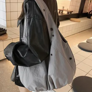 Minimalist light grey oversized nylon tote bag with metal eyelets worn by a model