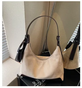 Detail of minimalist beige suede hobo bag with dark brown leather trim and mini pouch