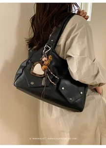 Detail of retro black tote bag with silver studs and heart mirror charm decoration