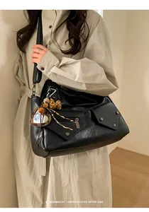 Detail of retro black hobo bag with zip pockets and heart leopard charm accessory