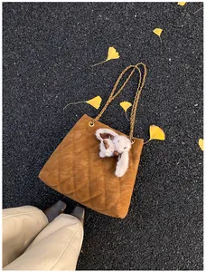 Detail van de gewatteerde bruine suède tas met gouden ketting en konijnenhanger
