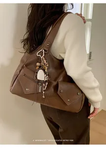 Detail view of a retro brown faux leather tote bag with heart leopard charm and scarf