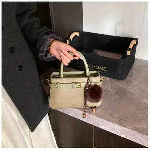 Detail of green woven bucket bag with leather handles and gold-tone hardware