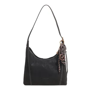 Black suede hobo bag with contrast stitching and decorative charms for daily commute
