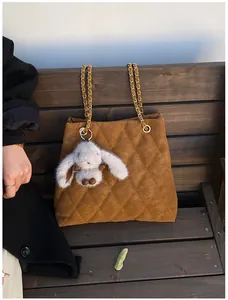 Detail van de bruine gewatteerde suède tote tas met gouden ketting en konijnenhanger