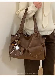 Detail of retro brown tote bag with metal rivet pockets and leopard heart charm