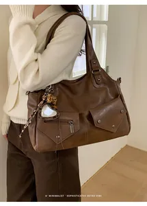 Detail of dark brown leather tote with rivet pockets and leopard heart charm