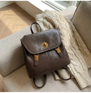 Detail of vintage brown leather backpack with golden twist lock on a soft sofa