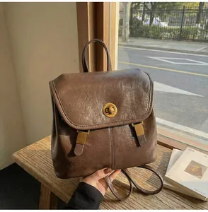 Detail of vintage brown leather backpack showing gold twist lock and buckle straps
