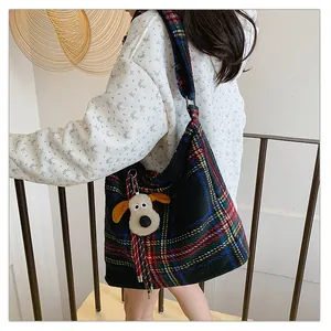 Close-up of a large tartan plaid tote bag with wide strap and plush dog pendant