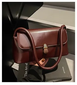 Macro detail of wine red glossy leather handbag with vintage gold buckle and dual handles