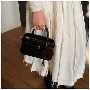 Detail of black leather bucket bag with gold hardware and brown fur charm