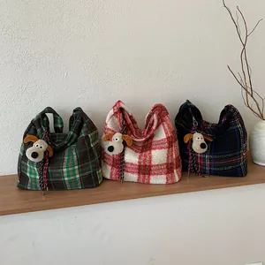 Plaid plush tote bags with cartoon charms shown in three colors on a wooden stand