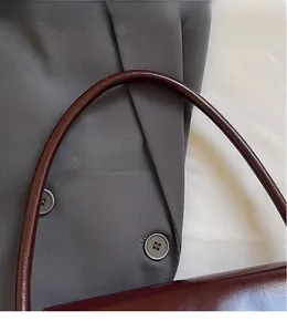 Close-up of glossy leather strap and texture on vintage burgundy underarm shoulder bag